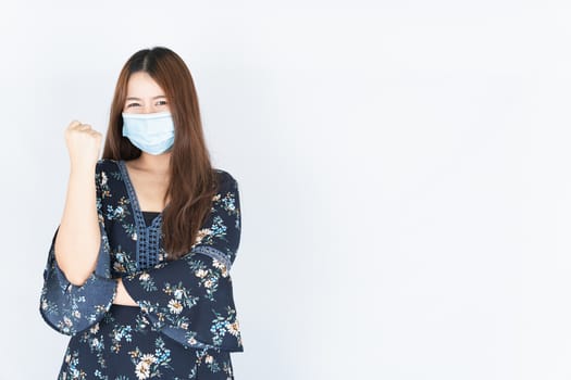 Asian beautiful happy hipster woman wearing a medical protection face mask for protect the coronavirus, filter dust PM 2.5 and cold and raise her hand to fight them on white background