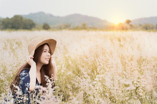 Summer portrait of young hipster woman sitting in meadow on sunny day.young slim beautiful woman, bohemian outfit, indie style, summer vacation, sunny, having fun, positive mood, romantic, woman in hat