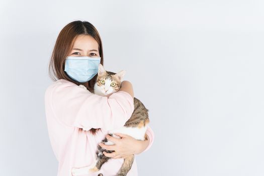 Asian beautiful happy woman wearing a medical protection face mask for protect the coronavirus, filter dust PM 2.5, cold and allergic to cat fur and she carry a cat on the white background