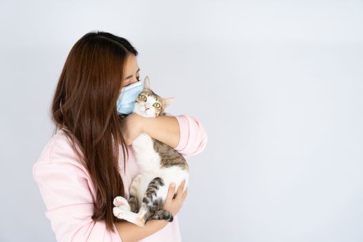 Asian beautiful happy woman wearing a medical protection face mask for protect the coronavirus, filter dust PM 2.5, cold and allergic to cat fur and she carry a cat on the white background