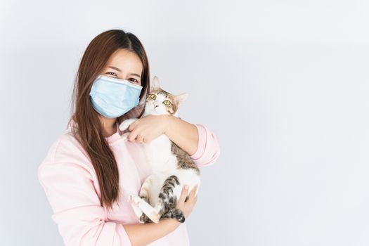 Asian beautiful happy woman wearing a medical protection face mask for protect the coronavirus, filter dust PM 2.5, cold and allergic to cat fur and she carry a cat on the white background