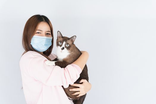 Asian beautiful happy woman wearing a medical protection face mask for protect the coronavirus, filter dust PM 2.5, cold and allergic to cat fur and she carry a cat on the white background