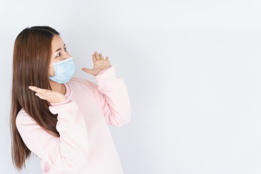 Asian beautiful happy hipster woman wearing a medical protection face mask for protect the coronavirus, filter dust PM 2.5 and cold and raise her hand to cheer up on white background