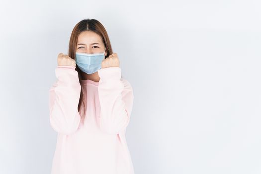 Asian beautiful happy hipster woman wearing a medical protection face mask for protect the coronavirus, filter dust PM 2.5 and cold and raise her hand to fight them on white background