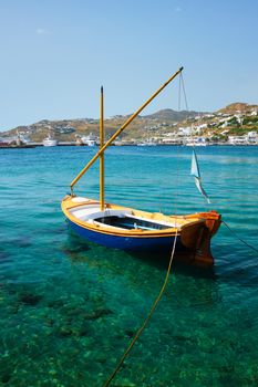 Greek fishing boat in clear sea water in port of Mykonos. Chora town, Mykonos, Greece