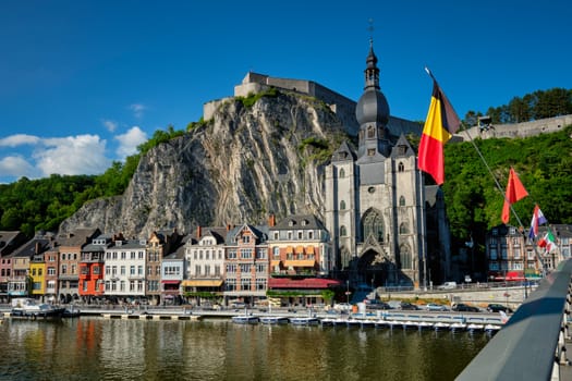 View of picturesque Dinant town, Dinant Citadel and Collegiate Church of Notre Dame de Dinant over the Meuse river with belgium flag. Belgian province of Namur, Blegium