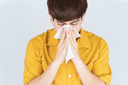 Asian handsome happy hipster man blowing a nose to tissue paper from the coronavirus, dust PM 2.5 and cold on white background