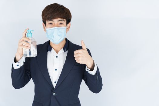 Asian handsome happy business man wearing a medical protection face mask for protect the coronavirus, filter dust PM 2.5 and cold and showing sanitizer hand gel and thumbs up on white background