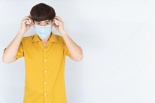 Asian handsome happy hipster man wearing a medical protection face mask for protect the coronavirus, filter dust PM 2.5 and cold on white background