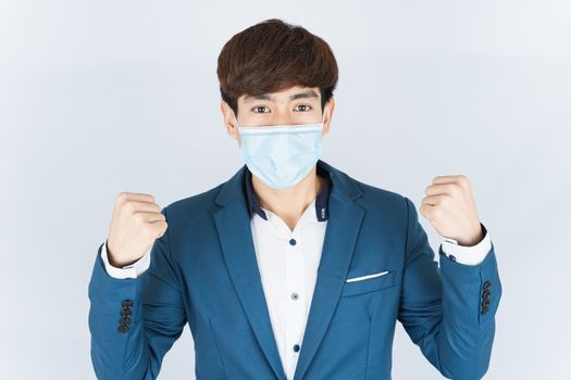 Asian handsome happy business man wearing a medical protection face mask for protect the coronavirus, filter dust PM 2.5 and cold and raise her hand to fight them on white background