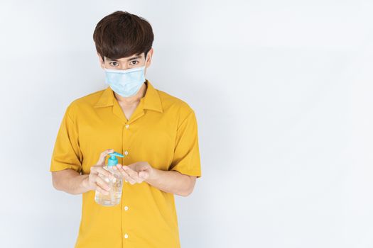 Asian handsome happy hipster man wearing a medical protection face mask for protect the coronavirus, filter dust PM 2.5 and cold and using sanitizer hand gel on white background