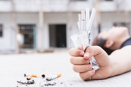 Close-up young woman 's hand crushes pack of cigarette and lying on the floor. World no tobacco day.