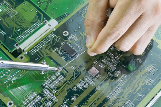 Technicians are using a soldering iron for repairing electronic of the computer circuit board concept technology of computer circuit hardware.
