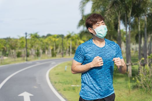 Young male wearing medical mask while running workout session at the park. Stay in fit during quarantine in the days of the Corona Virus or Covid-19