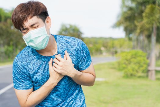 Young male wearing medical mask have headache while workout at the park. Stay in fit during quarantine in the days of the Corona Virus or Covid-19