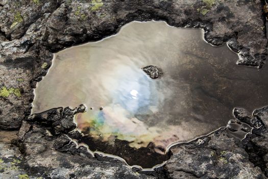 Dirty and oily water hole in stony landscape and nature of Norway.