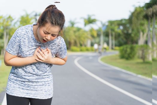 Exhausted female runner suffering painful angina pectoris or asthma breathing problems after training hard on summer. Running over training consequence.