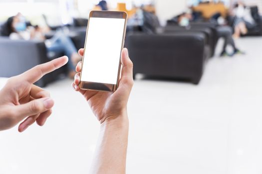 Close-up hands holding white blank screen smartphone in market store. Mockup smartphone on male hands empty display with the blur background.