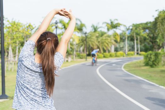 Young female stretching her arms before workout training session at the park. Healthy young woman warming up outdoors. Healthy and Lifestyle Concept.
