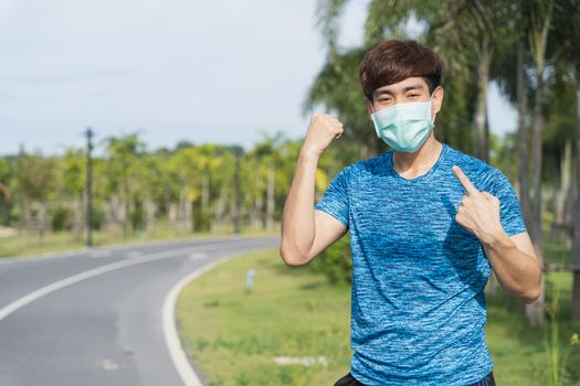 Young male wearing medical mask and show her hand to fight them before workout training session at the park. Stay in fit during quarantine in the days of the Corona Virus or Covid-19