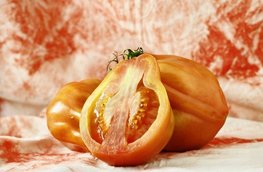 Red beefsteak tomatoes -beef tomato or coeur de boeuf -, large and flavor variety of tomato , ,in the foreground a tomato cut in half with bright seeds ,white- red background 