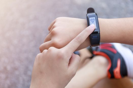 Close up Girl using smartwatch touching button and touchscreen on active sports. Finger touch button on smarth watch. Girl set smart watch before running on road.