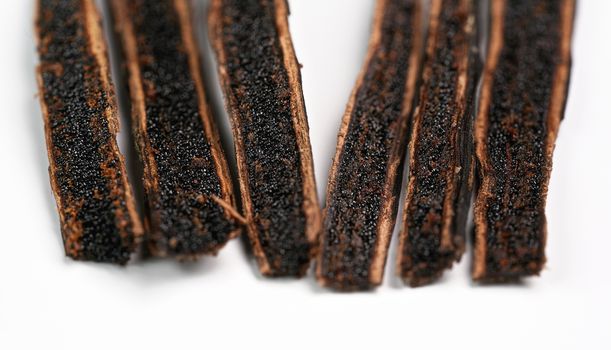 Vanilla pods cut with knife, black seeds visible, closeup detail photo isolated on white background.