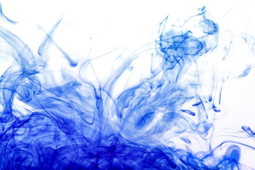 Blue ink injected from syringe, colour mixing with water creating abstract shapes, photo from aquarium tank.