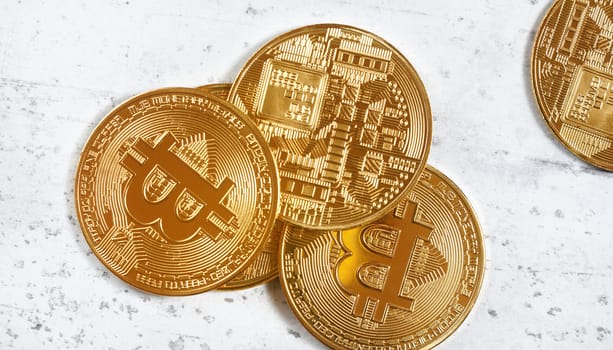 Overhead view, golden commemorative btc - bitcoin cryptocurrency - coins scattered on white stone board, closeup detail.