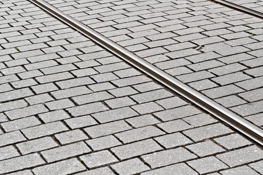 Detail on steel tram rail tiled stone floor around.