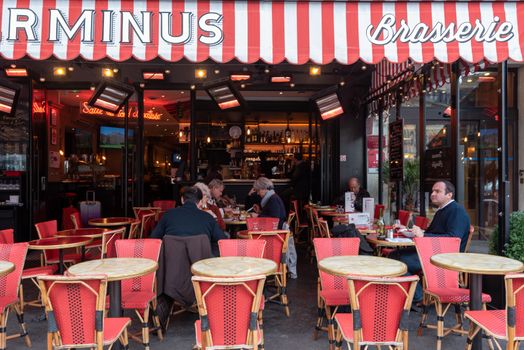 Paris, France -- November 4, 2017 -- Wide angle shot of Parisians dining in outdoors  in a brasserie on a pleasant Autumn afternoon. Editorial Use Only