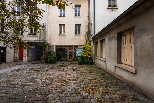 Ultra wide photo of a small courtyard behind some apartments ans shops in Paris.