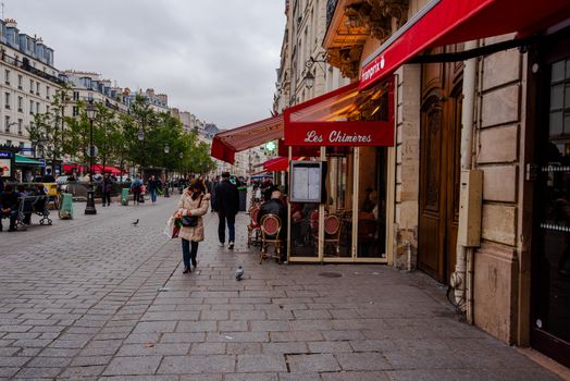 Paris, France -- November 4, 2017--A woman walks by a bistro along Rue St Antoine in Paris.