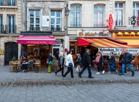 Paris, France -- November 4, 2017. Pedestrians walk along Rue St Antoine past bistros and bars.