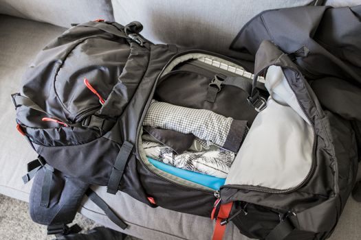 Packing travel backpack black red packed with clothes and travel utensils.