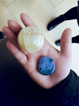 Girl holds blue and yellow stones and minerals in her hand.