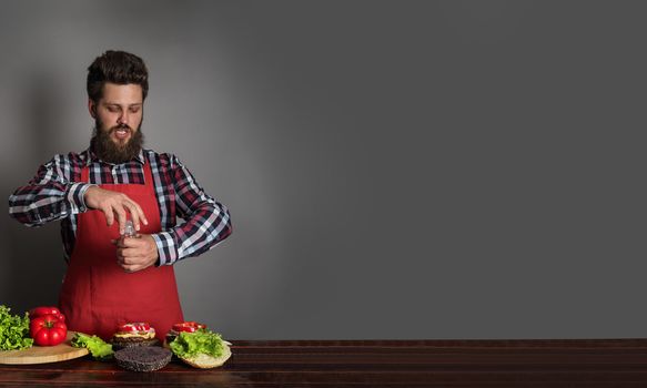 Man cooking fresh self made burgers gray background with copy space