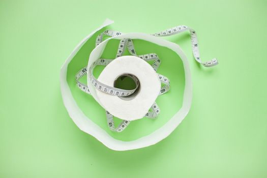 Diet and healthy eating concept. Top view of weightloss. Measuring tape and toilet paper. Capsules and diet pills. Green background