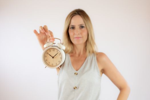 Young woman with short hair and casual clothes showing a clock