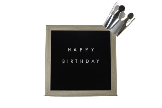 A Sign With a Birch Frame That Says Happy Birthday in White Letters With a Silver Crown on top on a Pure White Background