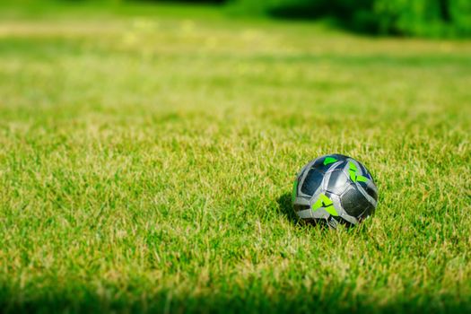 A Green and Black Soccer Ball in a Dreamy Grass Field During The Summer
