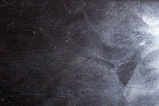 oily gloss black steel surface with many fingerprints - closeup with selective focus.