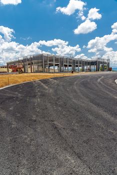 Vertical shot of a fresh blacktopped road leading up to a commercial construction site.