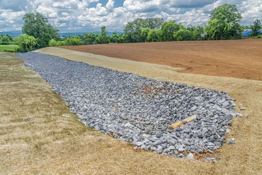 Horizontal shot of a rock lined ditch under construction.