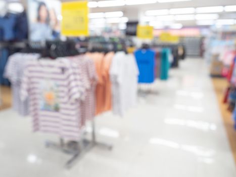 Supermarket blur background. Blurred interior view with walkway around with hanging clothes in shopping mall.