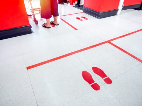 Red footprint and red line on floor in supermarket for warning for keep a safe social distance protect from Coronavirus, social distancing concept.