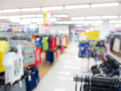 Supermarket blur background. Blurred interior view with walkway around with hanging clothes in shopping mall.