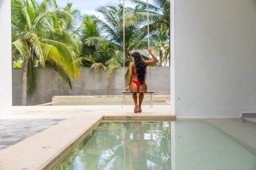 A beautiful brunette bikini model swings by the pool in the Yucatán Peninsula near Merida, Mexico