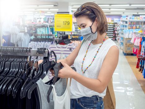 Beautiful asian women wearing protective face mask choosing to buy tank top, shopping in department store.