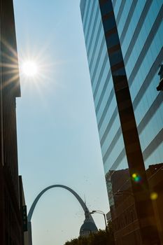 St Louis Gateway Arch at end of city street framed by high-rise buildings with sunburst. St Louis, architecture, and famous arch, Missouri,USA.